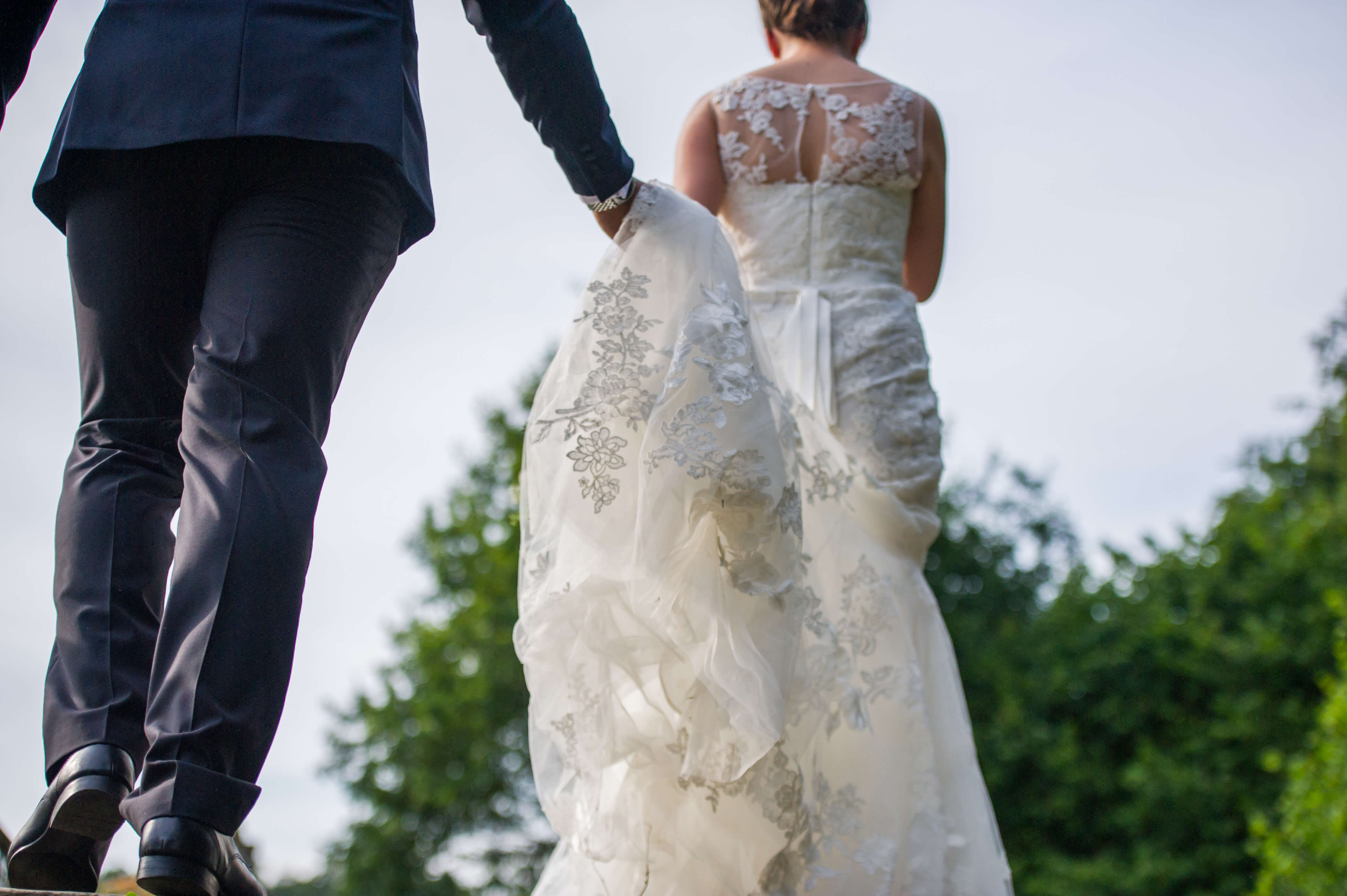 A groom holding his wife's bridal train in his hands 